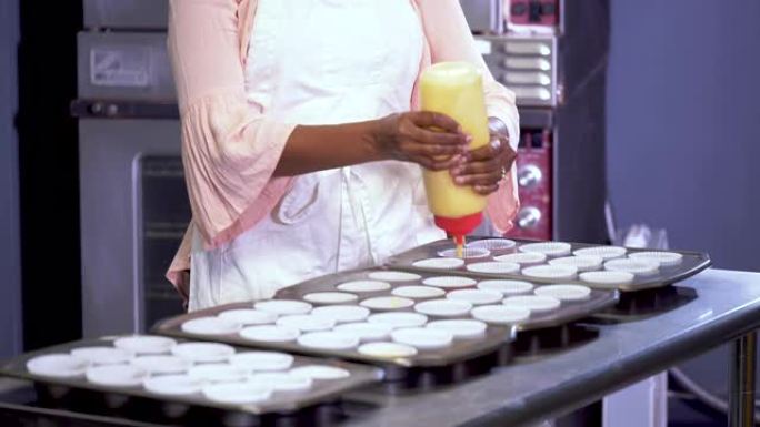 在面包店工作的非裔美国妇女制作纸杯蛋糕