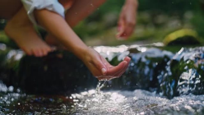 SLO MO年轻女子用手从溪流中舀出纯净水