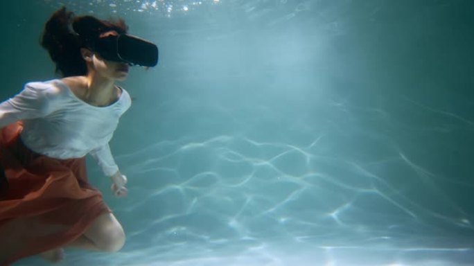 虚拟现实的概念。年轻迷人的混血女人使用VR耳机漂浮在水下慢动作深处。