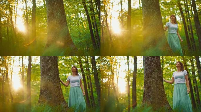 日落时分，穿着白色长裙的SLO MO女人在森林里散步时碰到树干
