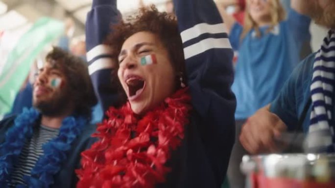 体育馆足球比赛: 美丽的双性恋球迷女孩肖像与意大利国旗彩绘的脸欢呼队获胜，击败铃鼓。人群庆祝进球，冠