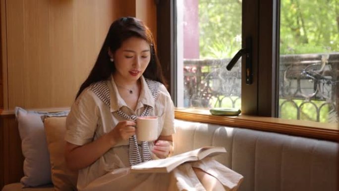 阅读和咖啡时间女人坐在沙发上靠窗看书读书