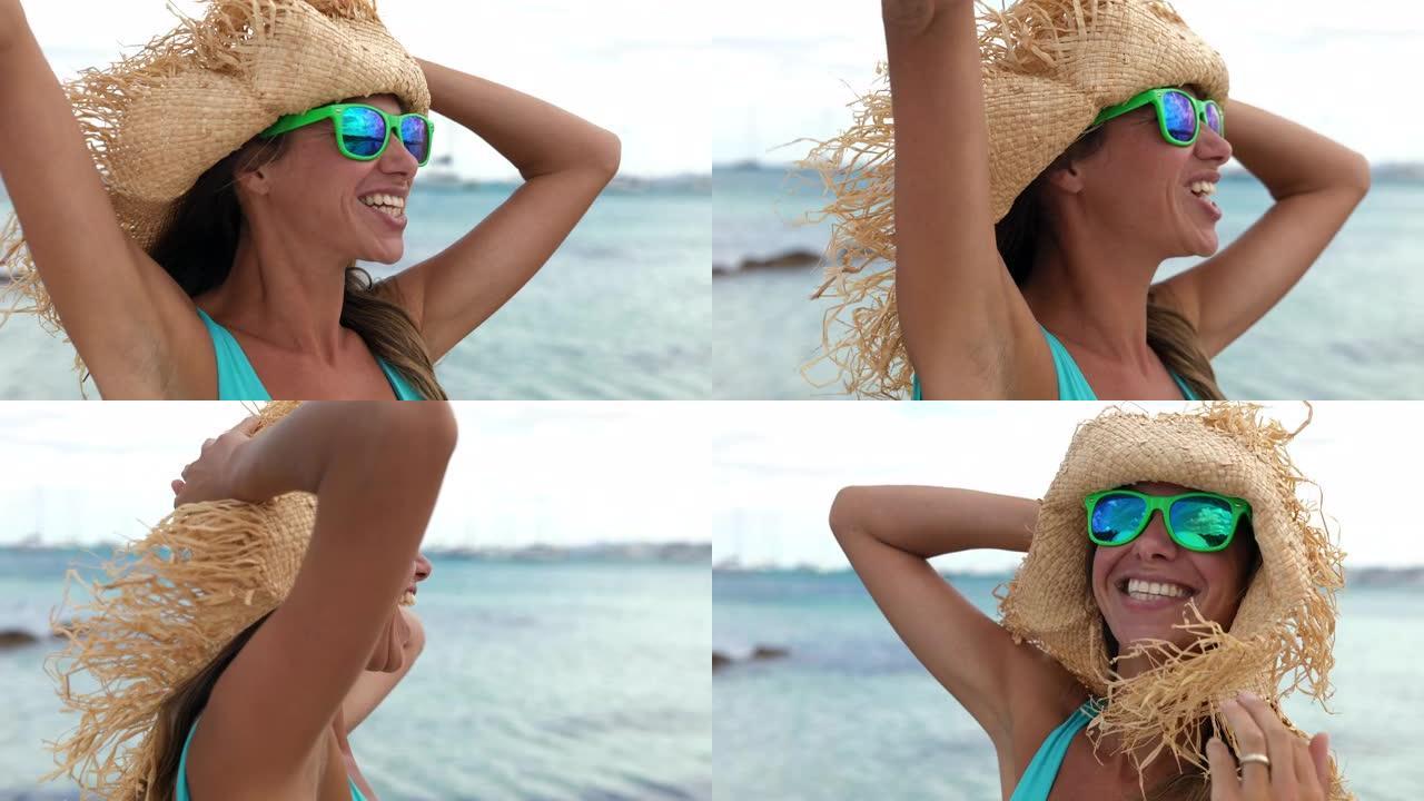 一个自然美丽的女人戴着夏日帽子在海滩上享受一天的真实照片。女性旅行者在阳光下度假时尖叫和庆祝