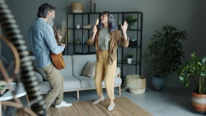 男人弹吉他，和在发刷里唱歌的女人跳舞，在家里玩得开心