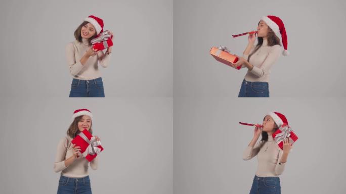 年轻的亚洲中国女性，戴着圣诞老人帽子，手持工作室灰色背景的圣诞礼物
