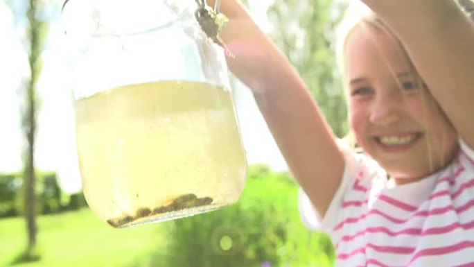 年轻女孩拿着装满蝌蚪的罐子的慢动作序列