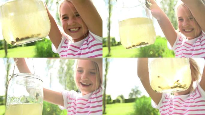 年轻女孩拿着装满蝌蚪的罐子的慢动作序列
