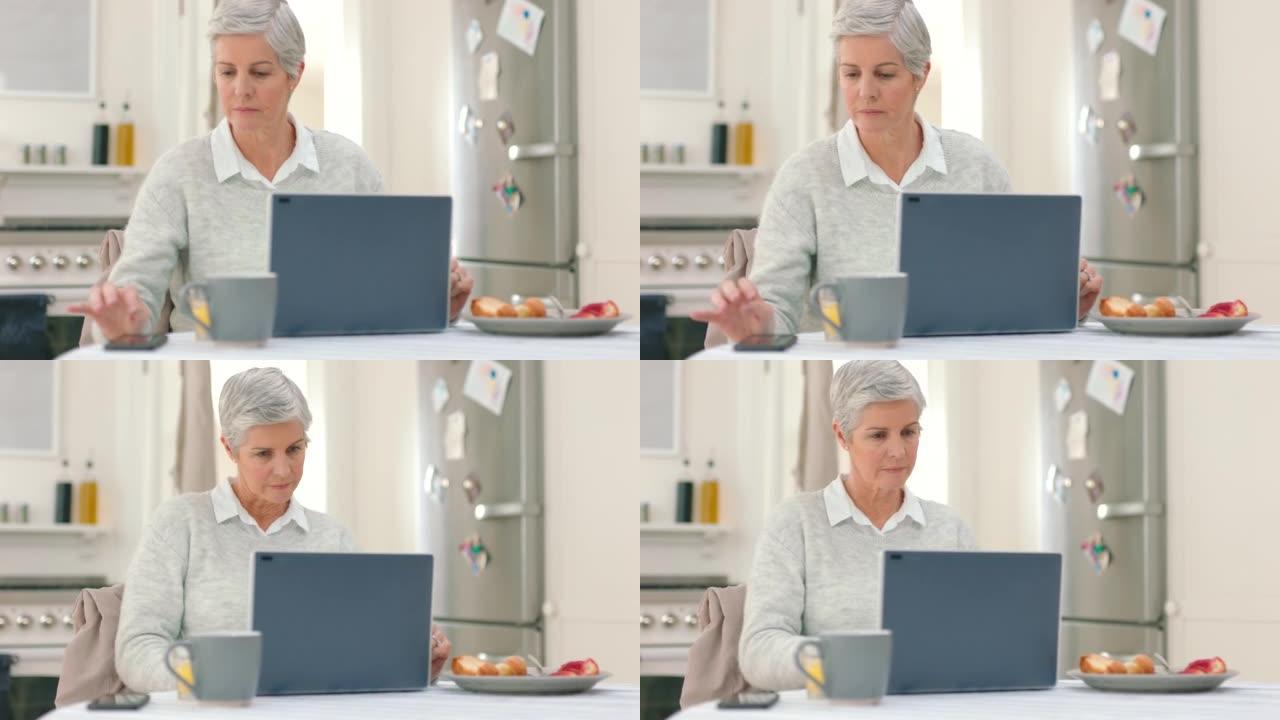 笔记本电脑，电话和早餐，一位资深女士正在考虑自己的意愿，并在厨房里为未来做计划。与在家工作的老年女性