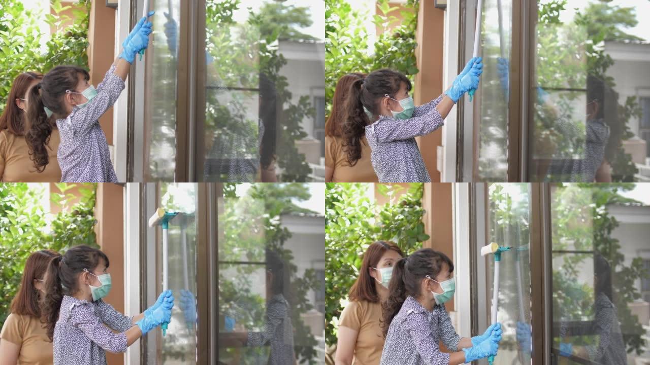 女儿帮助母亲清洁窗户上的玻璃