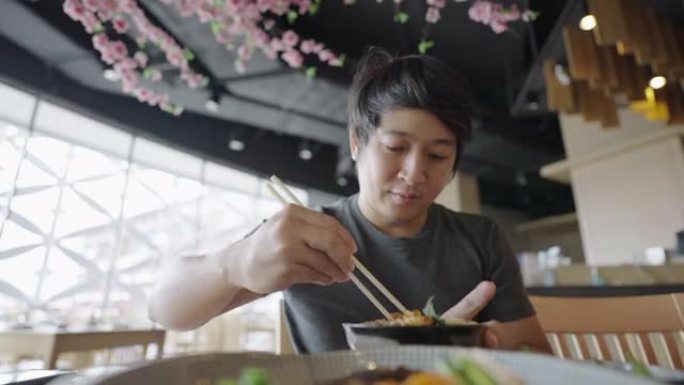年轻人分开筷子，在餐厅里尽情享用unagi donburi。