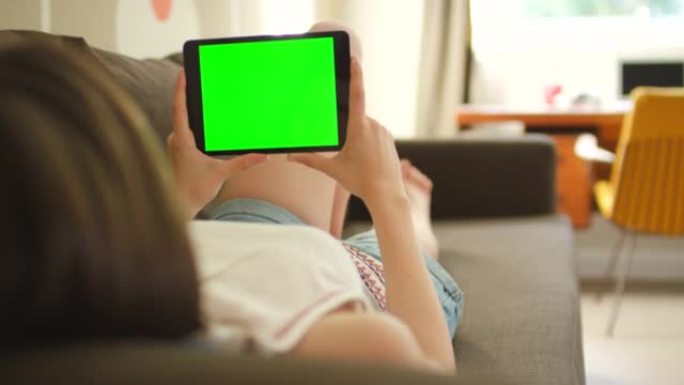 4k视频片段，一名妇女使用数字平板电脑躺在沙发上