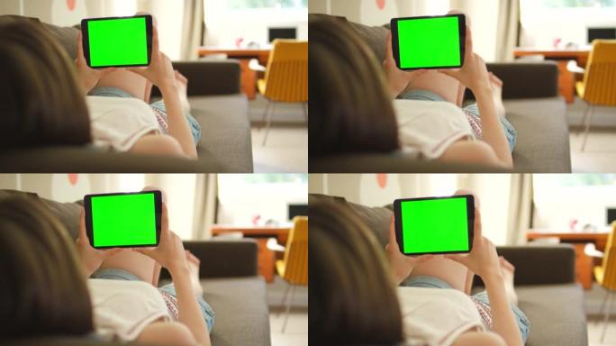 4k视频片段，一名妇女使用数字平板电脑躺在沙发上