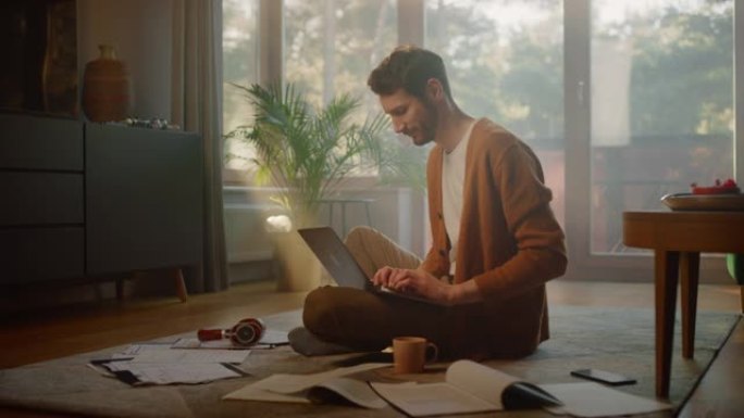 男人在家使用笔记本电脑，做远程工作。英俊的微笑男性坐在地板上工作的文件，文件，头脑风暴创意项目与研究