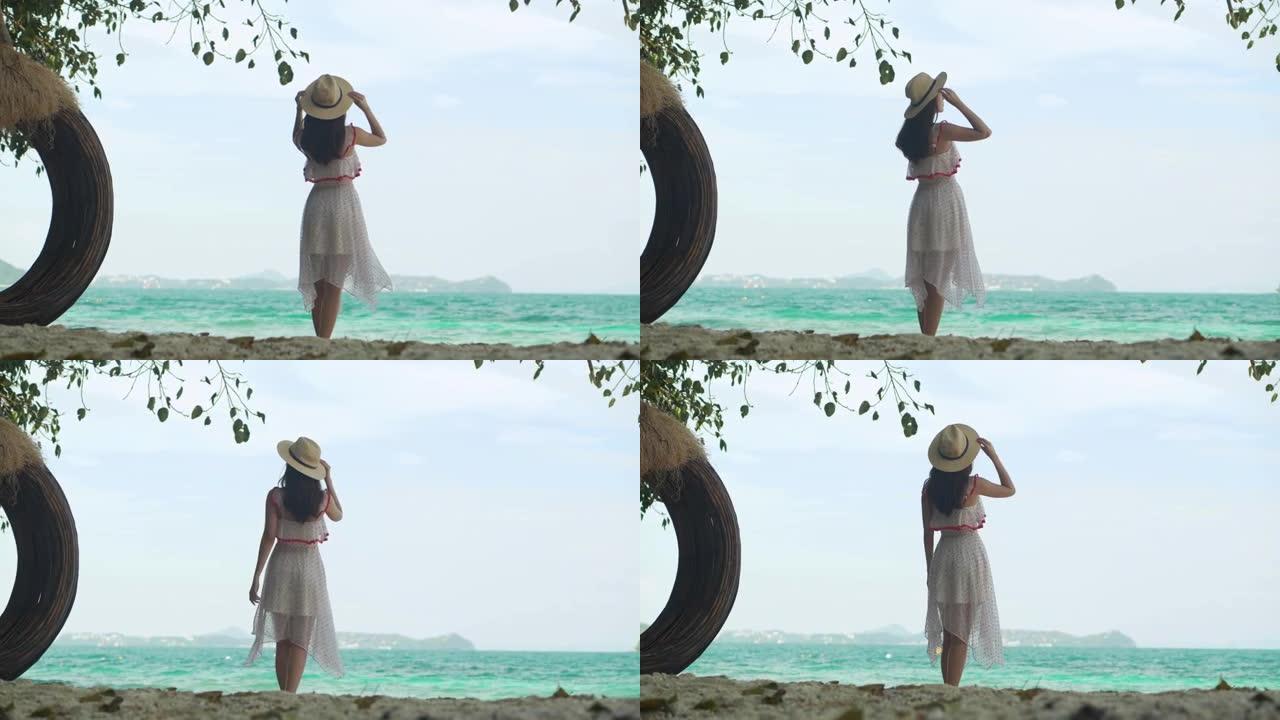 度假的背面视图亚洲年轻女性27岁的游客夏天在泰国普吉岛的度假胜地享受旅游假期，她看着海洋。她在海滩上