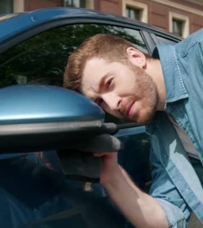 一位穿着牛仔裤衬衫的迷人红发汽车司机正在清洁车窗和后视镜