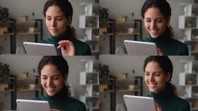 拿着平板电脑设备的漂亮女人微笑享受轻松的远程电子购物