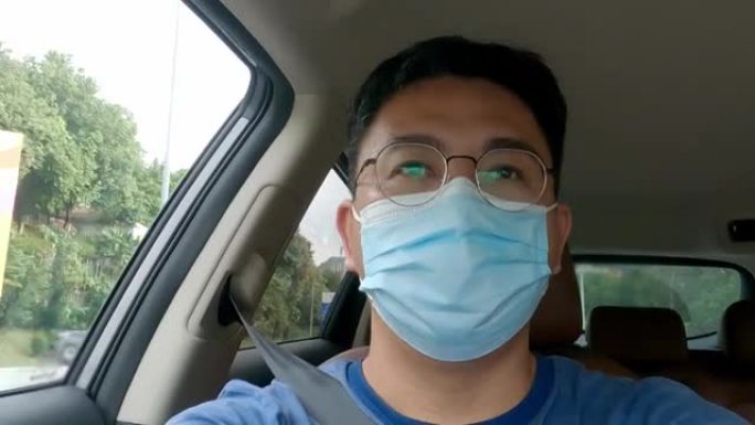 亚洲华人中年男子戴着面具独自在街上开车