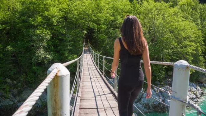 年轻女子越过山涧上的木制吊桥