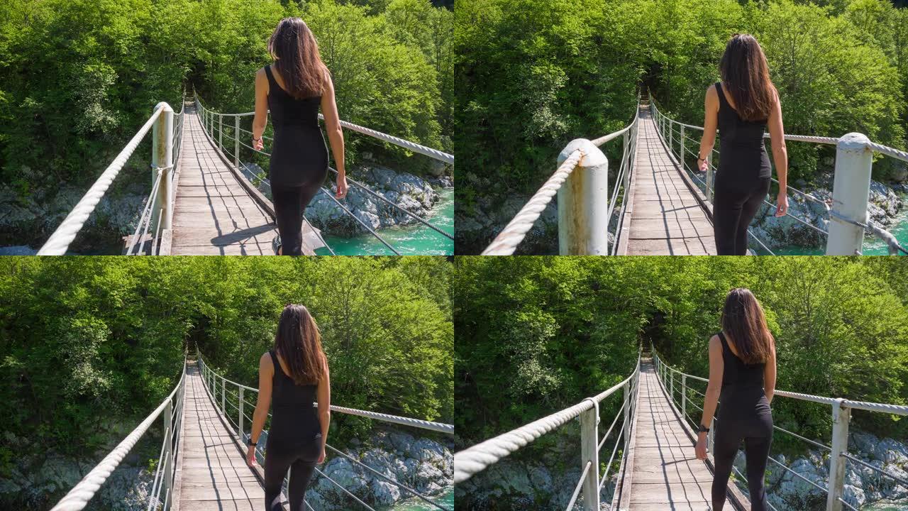 年轻女子越过山涧上的木制吊桥