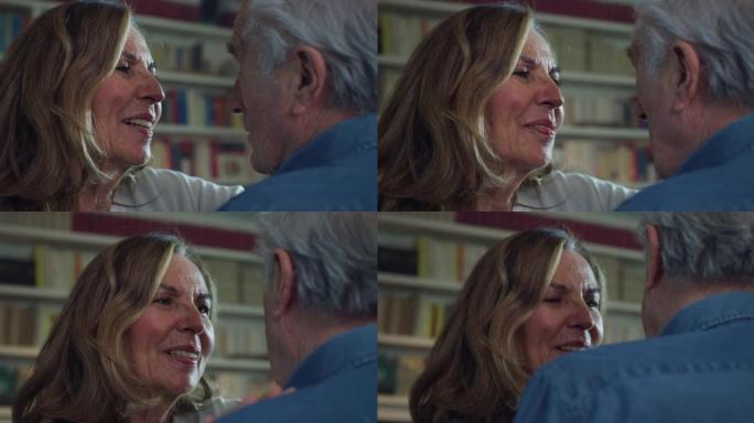 可爱的幸福成熟夫妇的电影特写镜头正在享受拥抱和亲吻的时光，这是家里客厅永恒爱情的标志。概念: 爱情，
