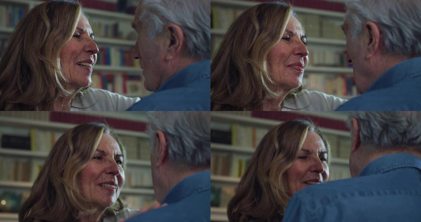 可爱的幸福成熟夫妇的电影特写镜头正在享受拥抱和亲吻的时光，这是家里客厅永恒爱情的标志。概念: 爱情，