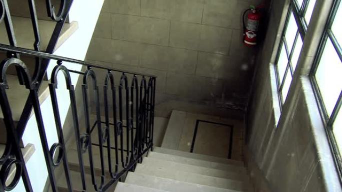 一栋旧公寓楼的楼梯内部，带有对称的楼梯和高天花板。