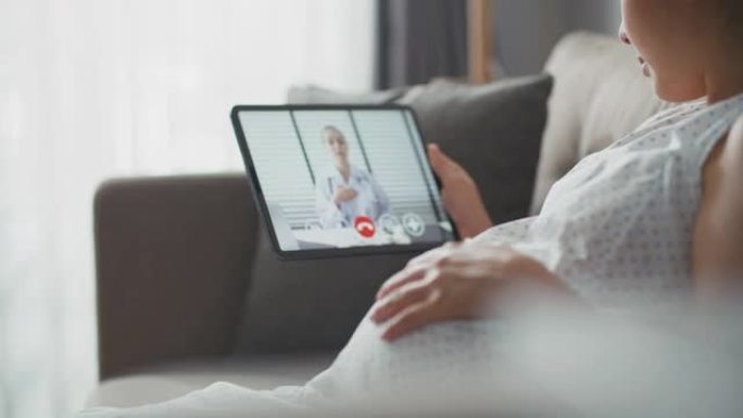 亚洲孕妇在家中与数字平板电脑上的医生进行视频通话