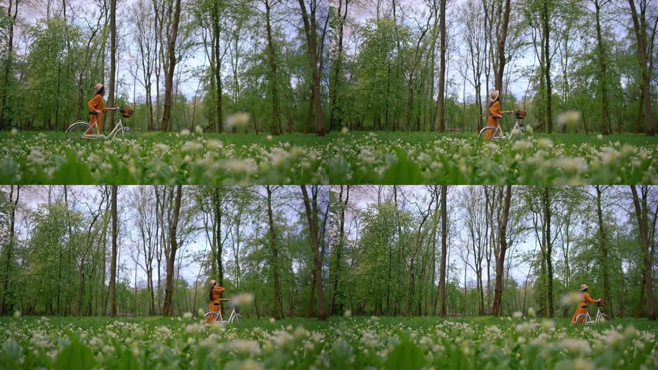 一个穿着橙色连衣裙的雄伟黑发女人的慢动作镜头，在森林里骑自行车