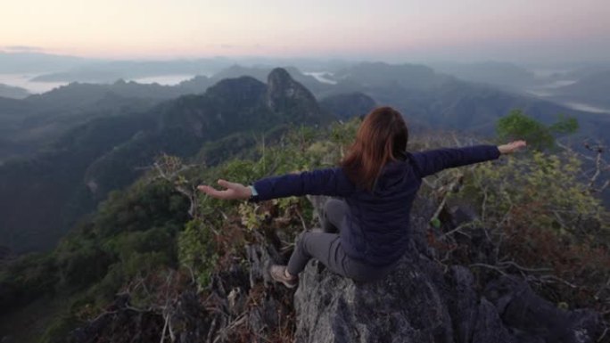 女人在山顶上徒步旅行，举手庆祝成功