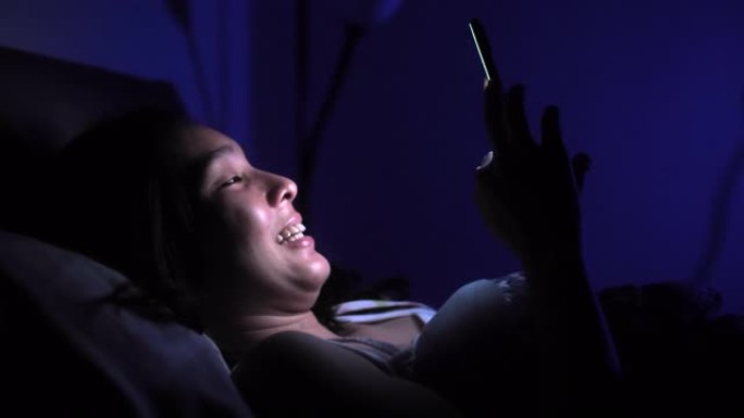 亚洲女性晚上睡觉前使用智能手机