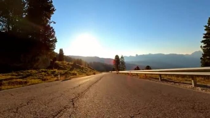 汽车在日出时在山口上空的空旷风景蜿蜒的道路上行驶