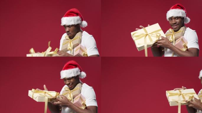 一个戴着圣诞帽的黑皮肤快乐的男人拿着一堆礼品盒微笑着