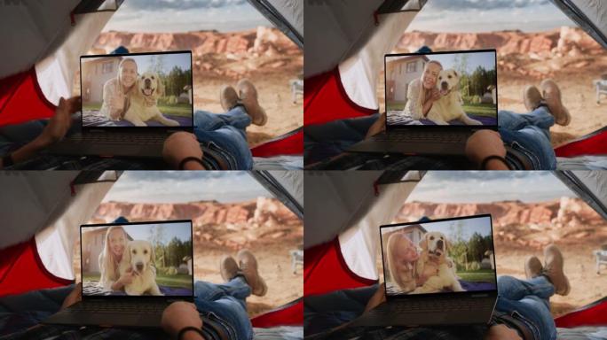一名游客与朋友在笔记本电脑上玩快乐狗的视频通话的视点镜头。旅行者在落基山顶上的帐篷里休息。生活在大自