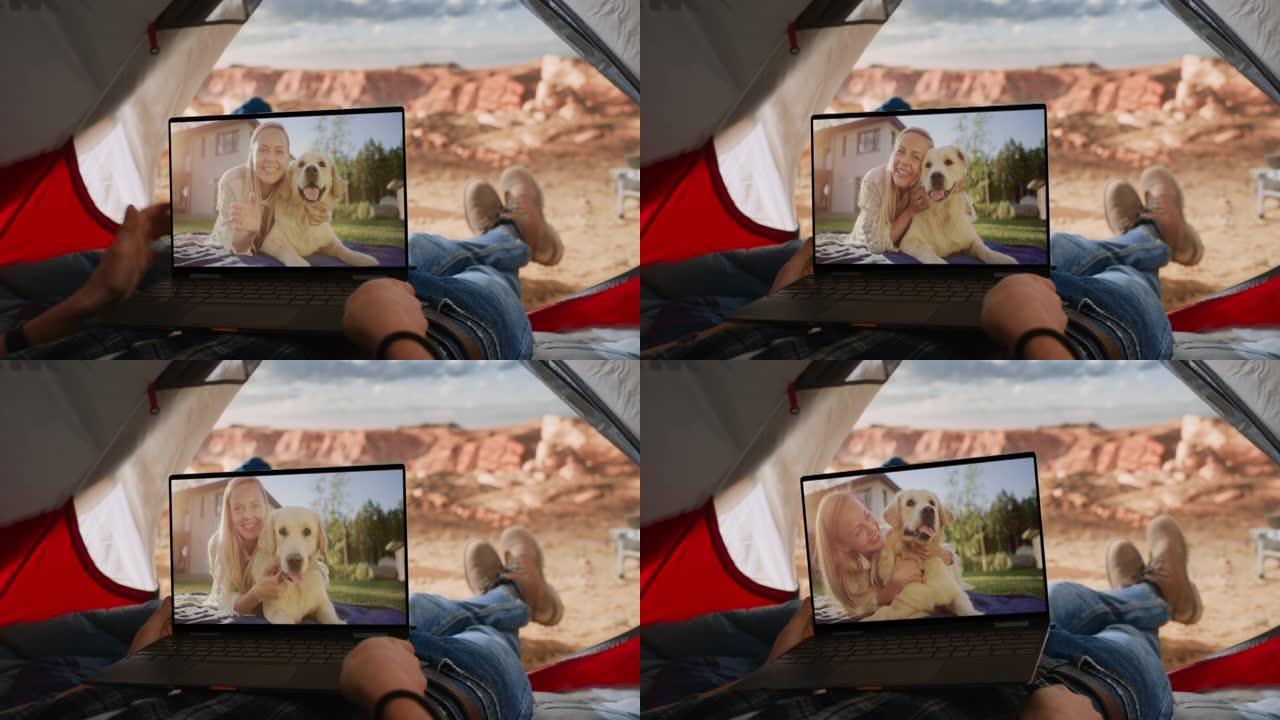 一名游客与朋友在笔记本电脑上玩快乐狗的视频通话的视点镜头。旅行者在落基山顶上的帐篷里休息。生活在大自