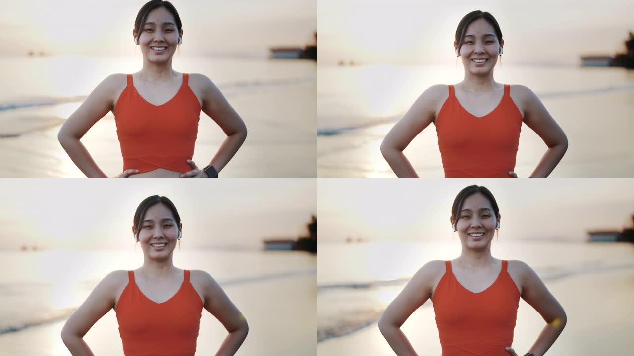 日落时在海滩上对着镜头微笑的运动女子肖像