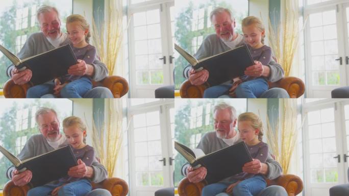 祖父和孙女一起在家里的休息室里翻看相册