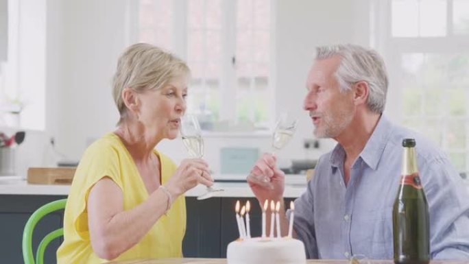 退休夫妇一起在家用一杯香槟和蛋糕庆祝生日