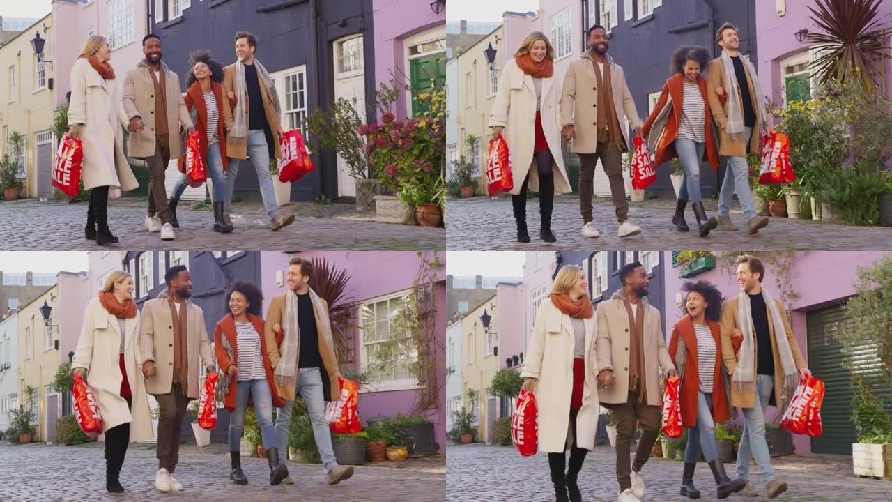 两对多元文化的夫妇在秋天或冬天参观城市时，手挽手走在鹅卵石的mews街上，带着出售购物袋-慢动作拍摄