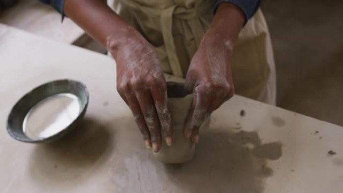 女陶工穿着围裙在陶艺工作室制作陶罐的特写镜头