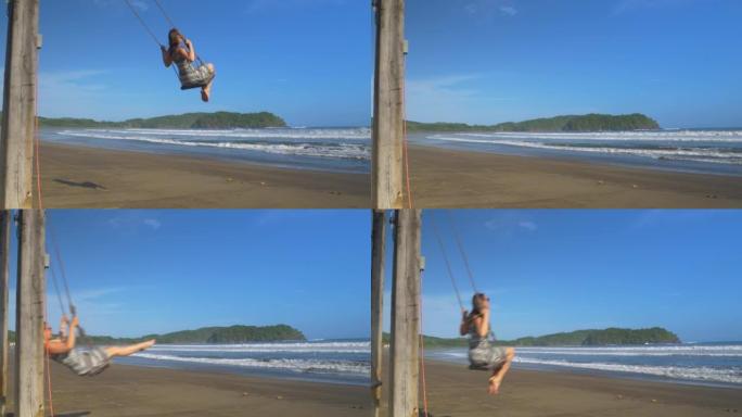 慢动作，低角度视角: 年轻女子在热带地区的海滩秋千上享受