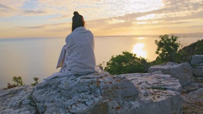 坐在悬崖上欣赏海景的年轻女子