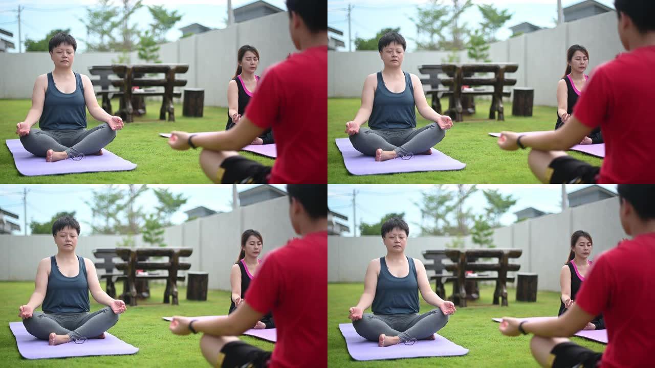 亚洲中国中年妇女与朋友一起练习瑜伽前院