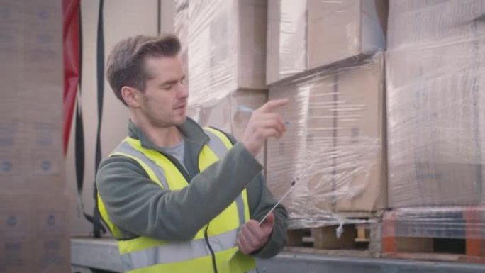 男性货运工人用剪贴板检查卡车是否装有箱子