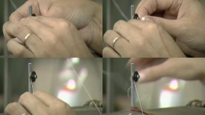 女人用手穿线缝纫机，在缝纫机上准备导线器以进行工作。特写。