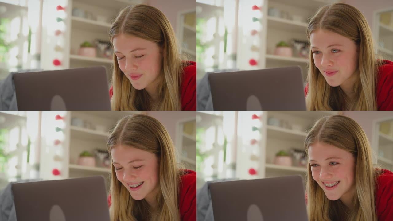 十几岁的女孩戴着正畸牙套躺在家里的床上，将电影流式传输到数字平板电脑上，并以慢动作大笑