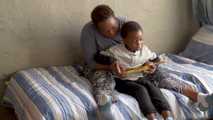南非新型冠状病毒肺炎冠状病毒大流行期间，非洲黑人妇女在家教育她可爱的小男孩