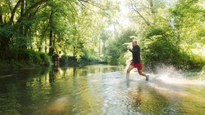 SLO MO Man在树林里跑过河