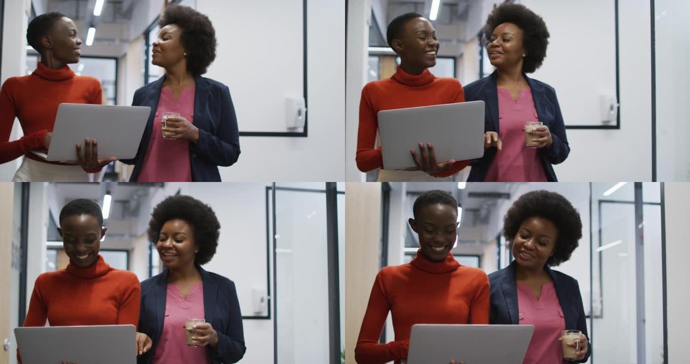 两名带笔记本电脑的非裔美国女办公室同事在办公室一起讨论