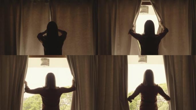 一个成熟的女人在家里放松的早晨打开卧室的窗帘。从新的一天开始，一位穿着剪影的高级女士的后视图看着窗外