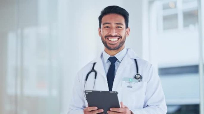 一位成功的男性医生在医院内的平板电脑上使用互联网发送处方。使用远程医疗的快乐医疗专业人员的肖像。GP